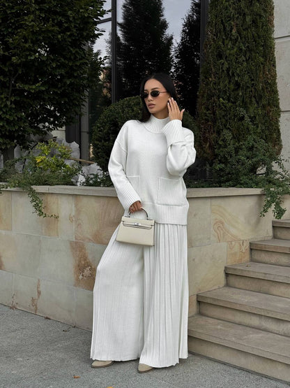 Woman in a white outfit standing outdoors with greenery and steps in the background