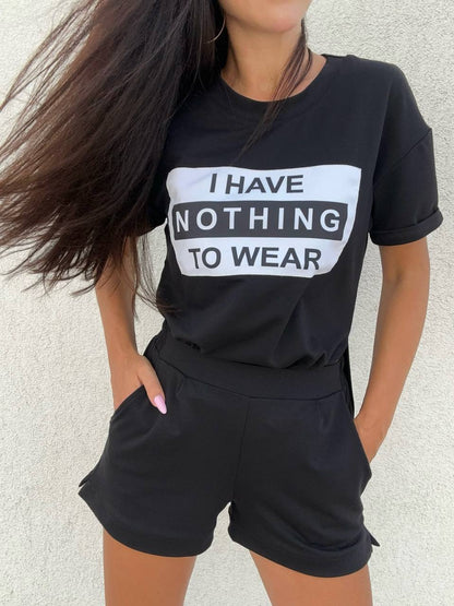 Person wearing a black t-shirt with 'I HAVE NOTHING TO WEAR' text and black shorts against a light background