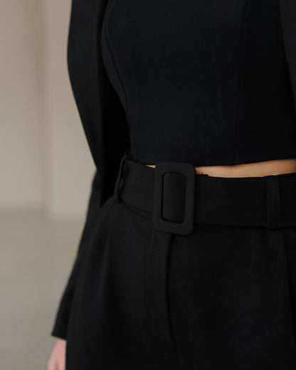 Black outfit with a belt on a neutral background