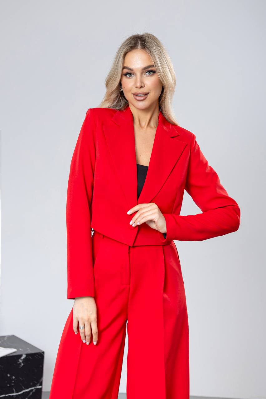Woman wearing a red suit against a light gray background