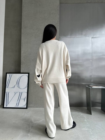 Person wearing a white outfit standing in a minimalistic room with a 'LOVE' sign on the wall.