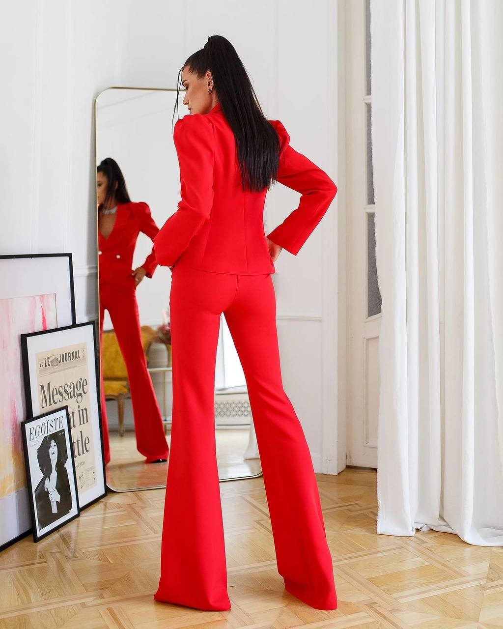 Person wearing a red outfit standing in a room with a mirror and decor.