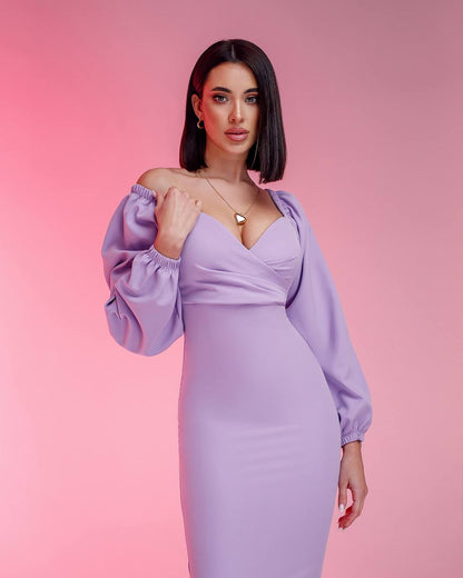 Woman wearing a lavender dress with balloon sleeves against a pink background
