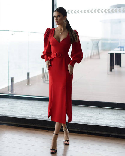 Woman in a red dress standing in a modern indoor setting with large windows.