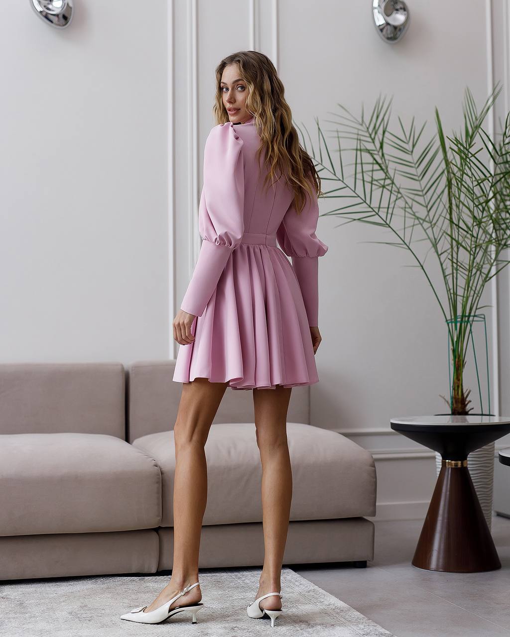Woman in a pink dress standing in a modern living room.