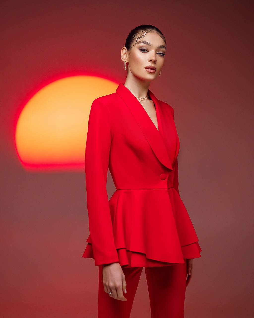 Woman in a red outfit standing against a sunset background