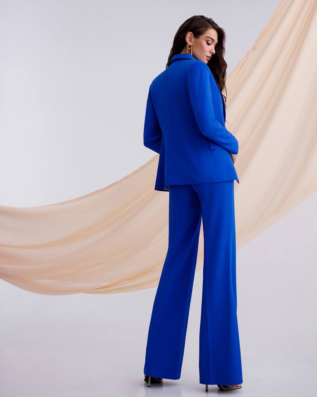 Woman wearing a blue suit standing against a plain background
