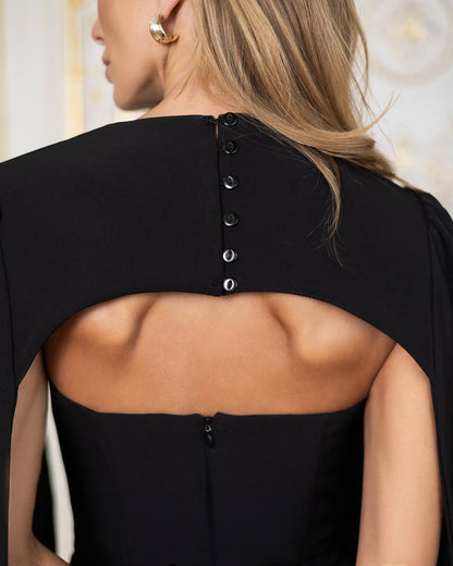 Black dress with open back and button details, worn by a person.