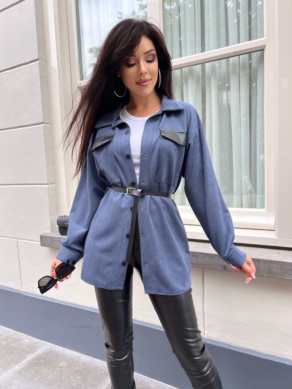 Woman wearing a blue denim shirt and black leather pants standing outdoors.