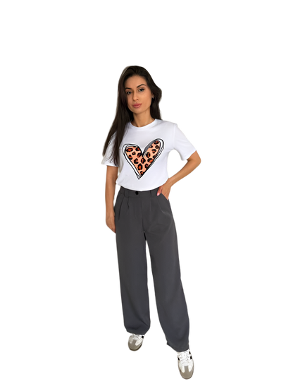 Woman wearing a white t-shirt with a heart design and gray pants on a white background