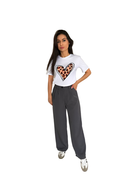Woman wearing a white t-shirt with a heart design and gray pants on a white background