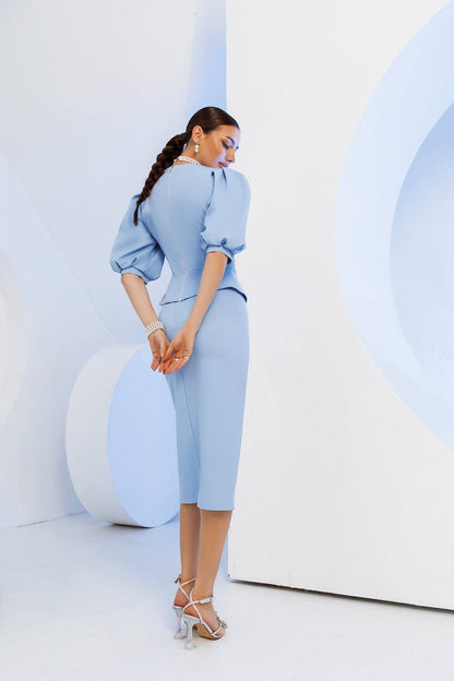 Woman in a light blue outfit standing against a white background