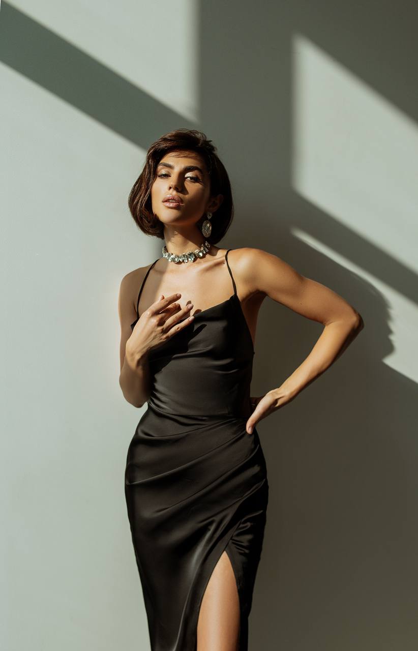 Woman in a black dress standing against a wall with shadows