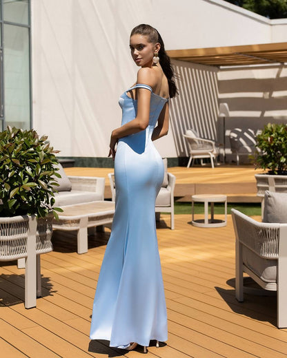 Woman in a light blue evening gown standing on a wooden deck with outdoor furniture.