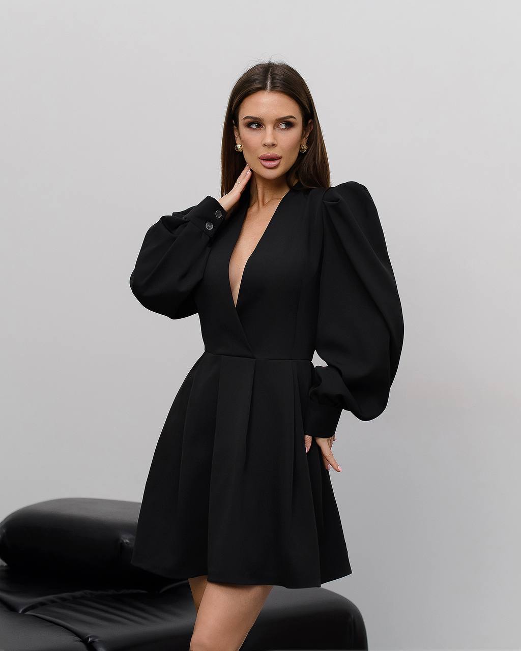 Woman wearing a black dress with puffed sleeves against a gray background