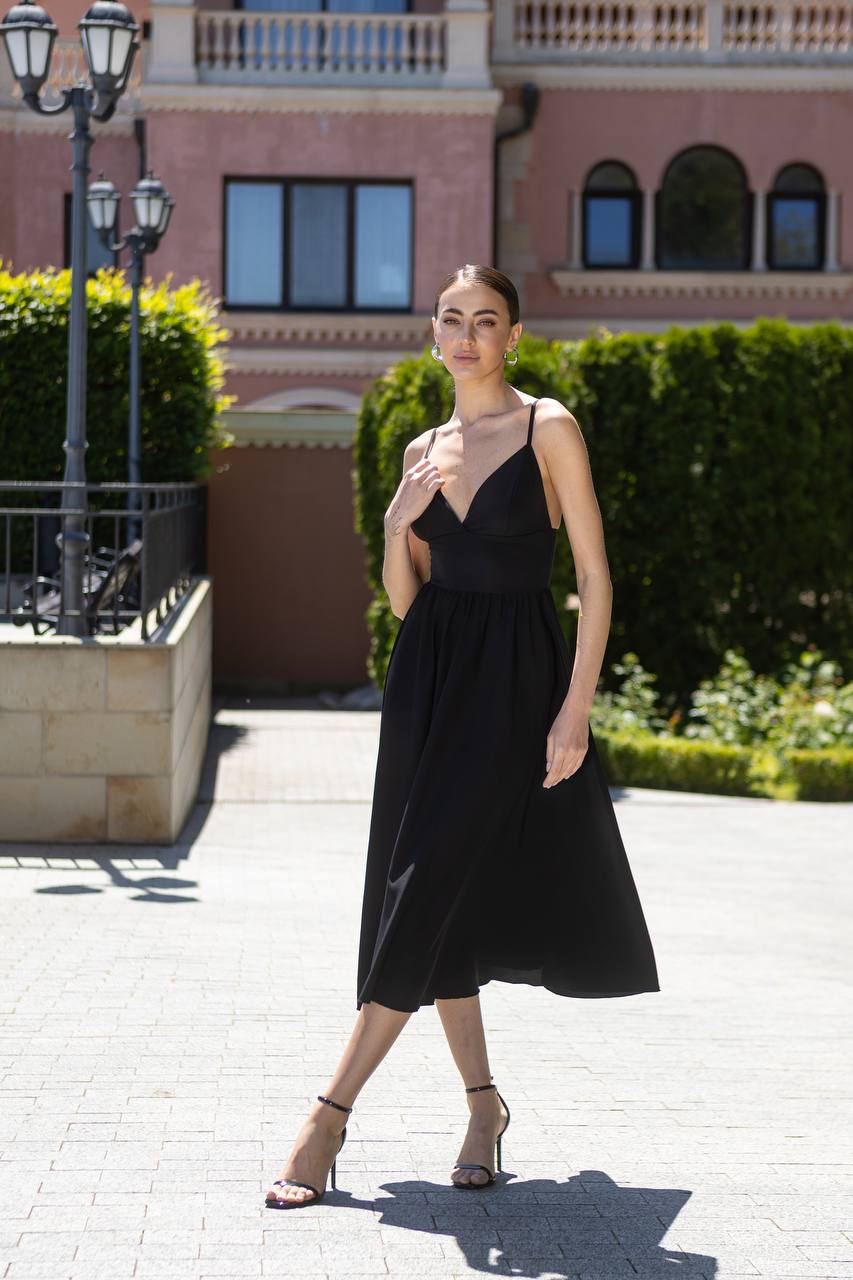 Woman in a black dress standing outdoors with a building in the background