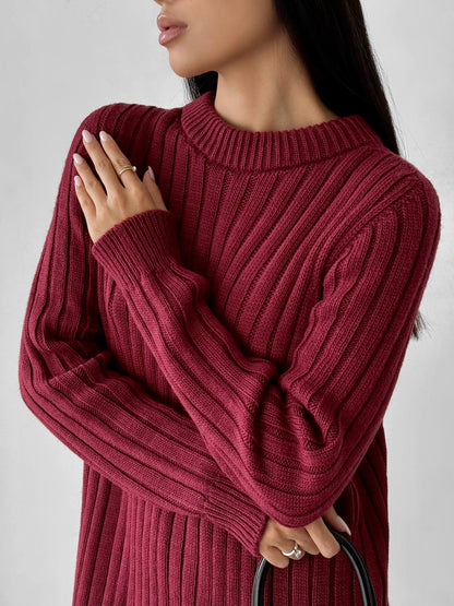 Person wearing a burgundy ribbed sweater against a plain background