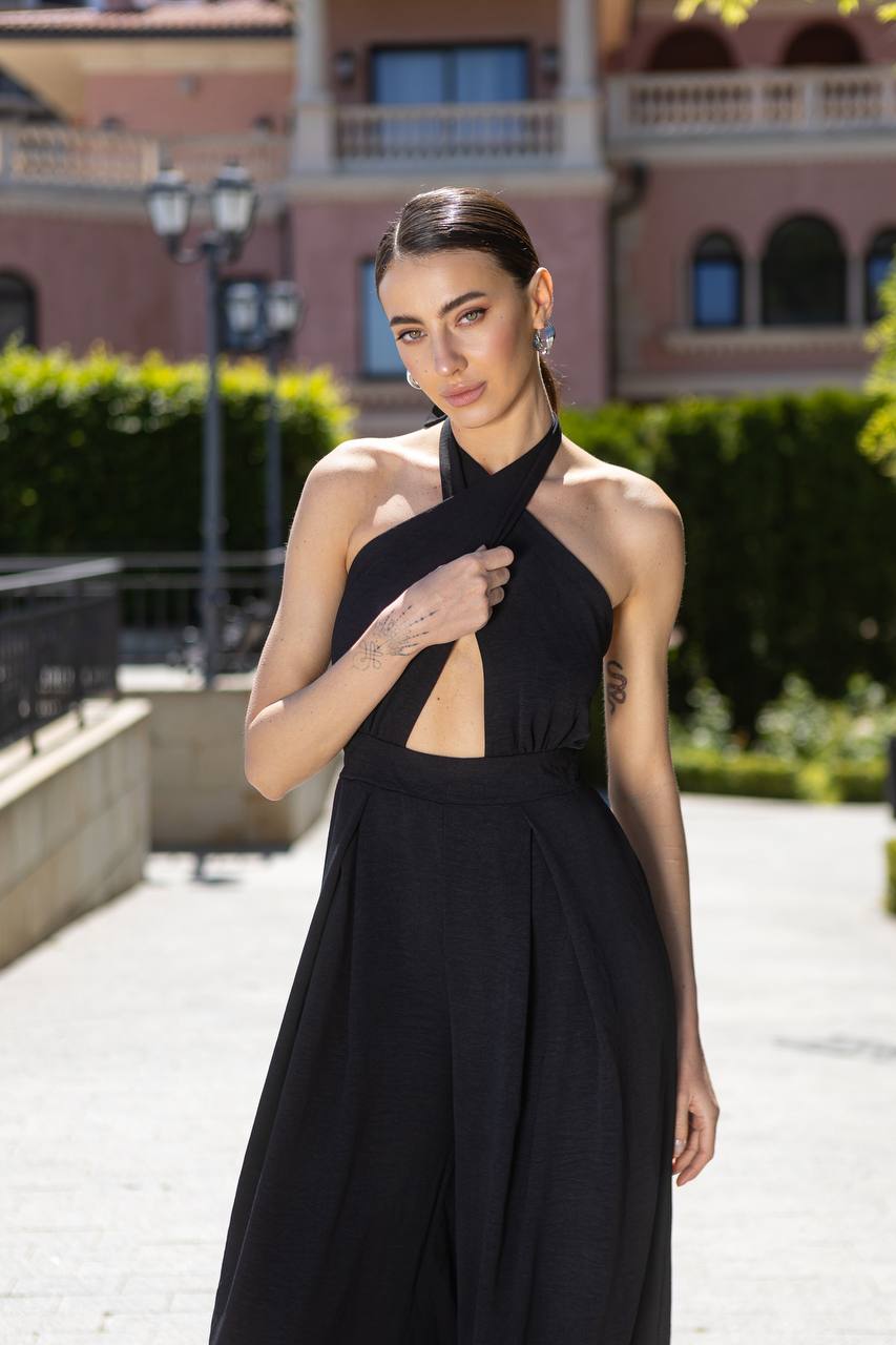 Woman in a black dress standing outdoors with a building in the background