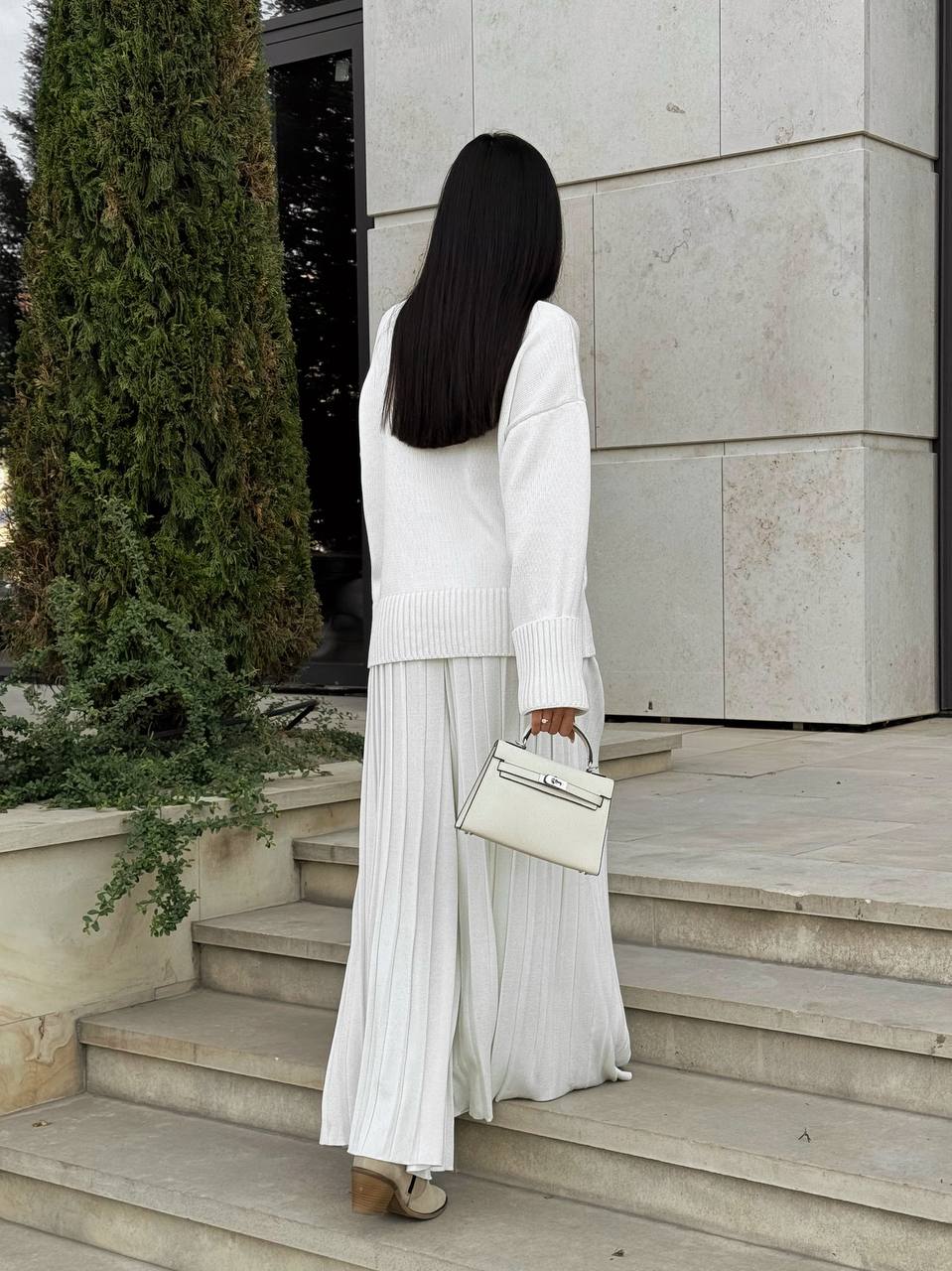 Woman in a white outfit standing on steps outside a building