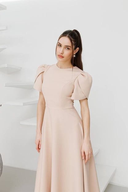 Woman wearing a beige dress against a white background