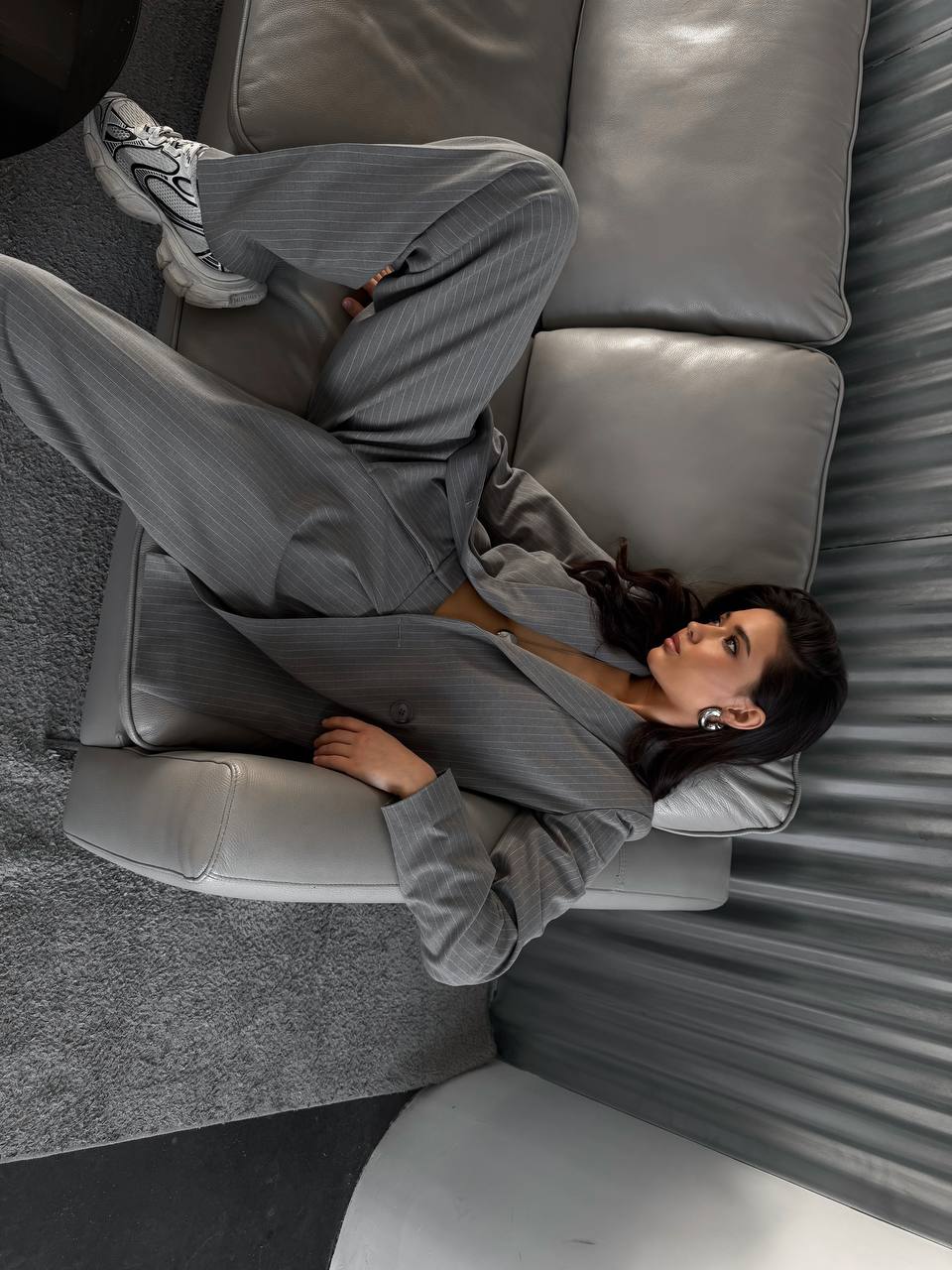Person wearing a gray suit sitting on a gray sofa.