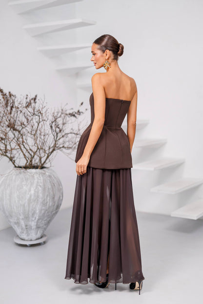 Woman wearing a brown strapless gown standing in front of a white abstract sculpture.