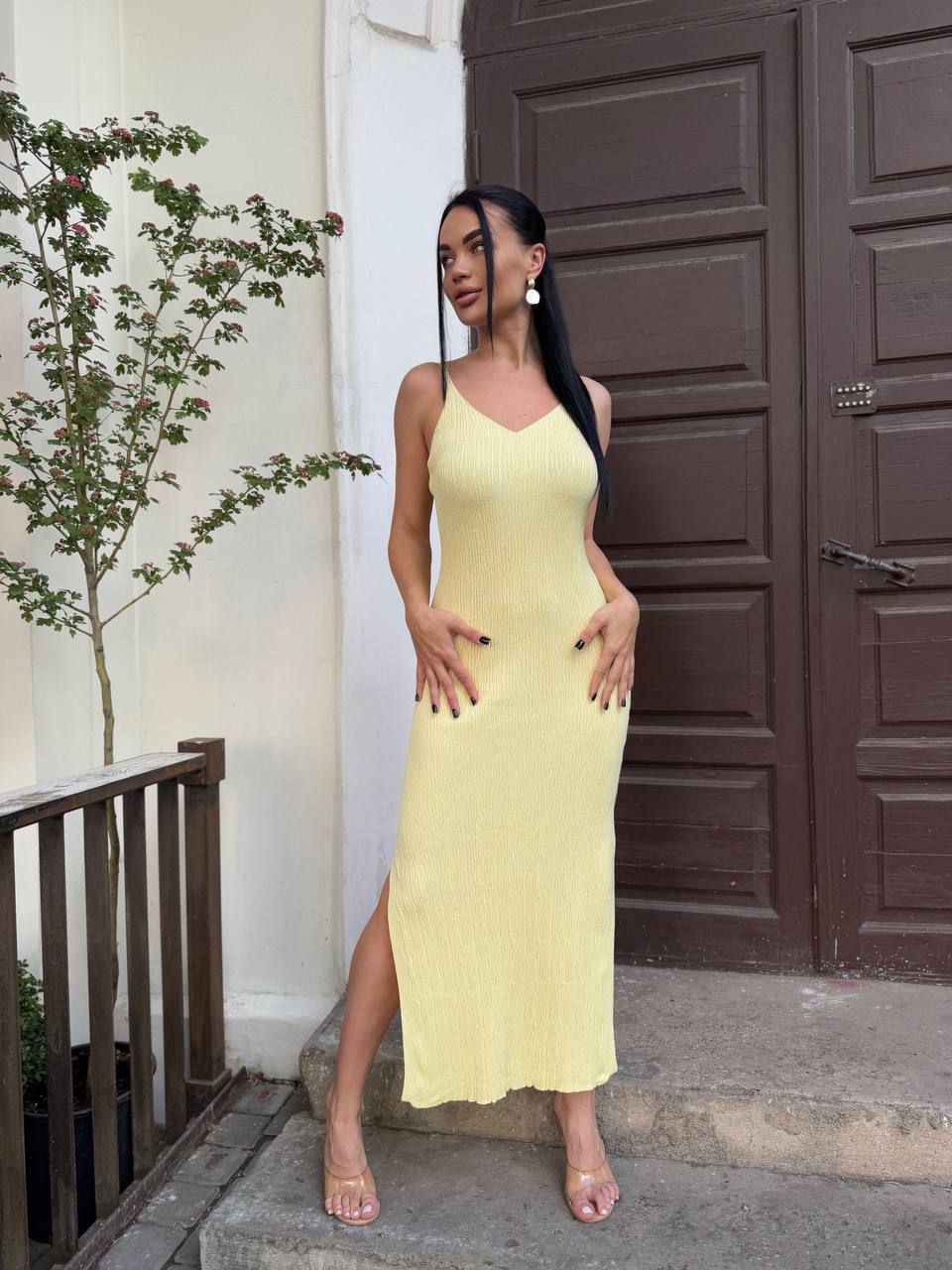 Woman in a yellow dress standing in front of a brown door.