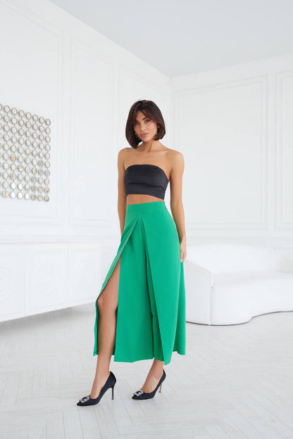 Woman wearing a black strapless top and green skirt in a minimalistic room.