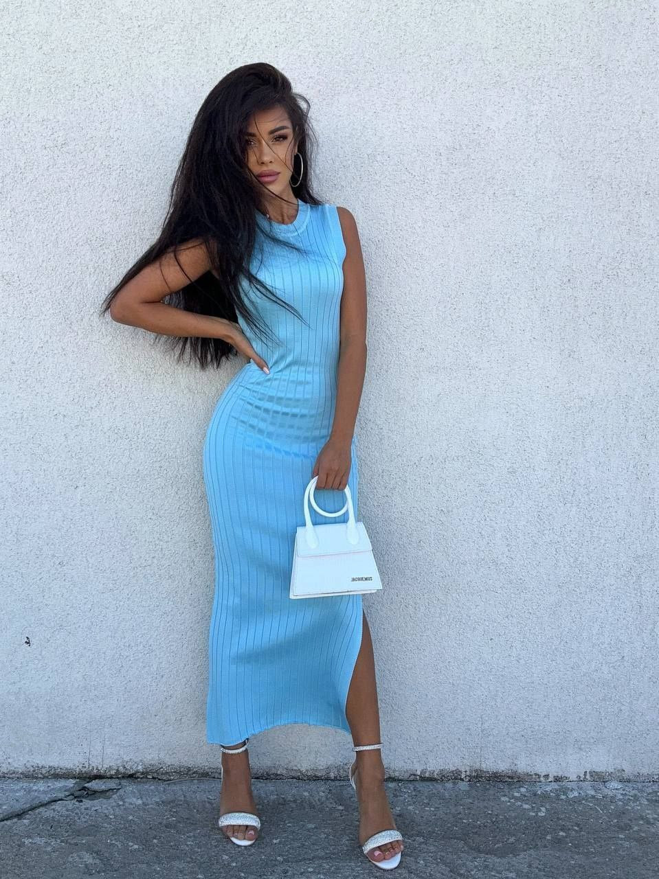 Woman in a light blue dress standing against a white wall