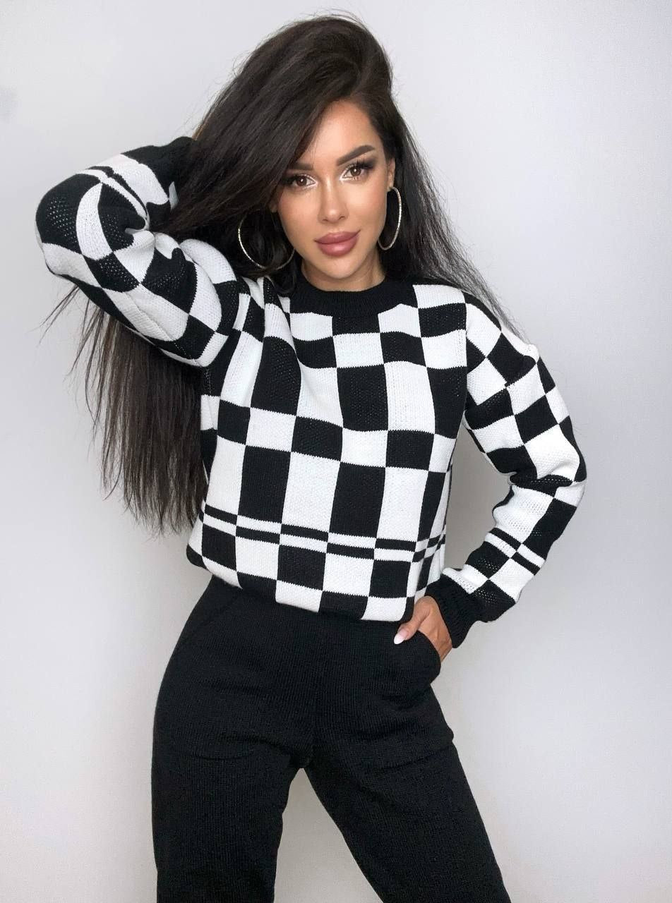 Person wearing a black and white checkered sweater against a plain background