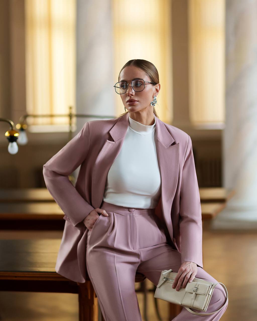 Woman in a pink suit sitting in an elegant interior setting