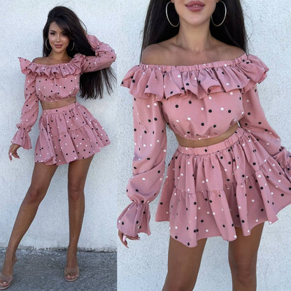 Pink polka dot dress with ruffled sleeves and neckline on a white background