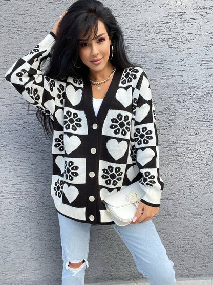 Woman wearing a black and white patterned cardigan against a gray wall.