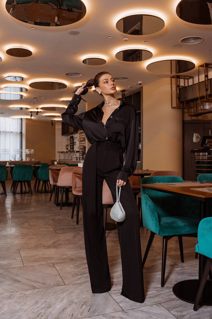 Woman in a black outfit standing in a stylish restaurant with modern decor.