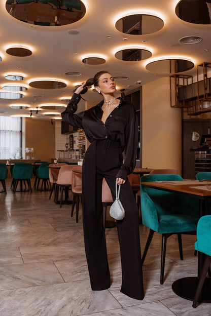 Woman in a black outfit standing in a stylish restaurant with modern decor.
