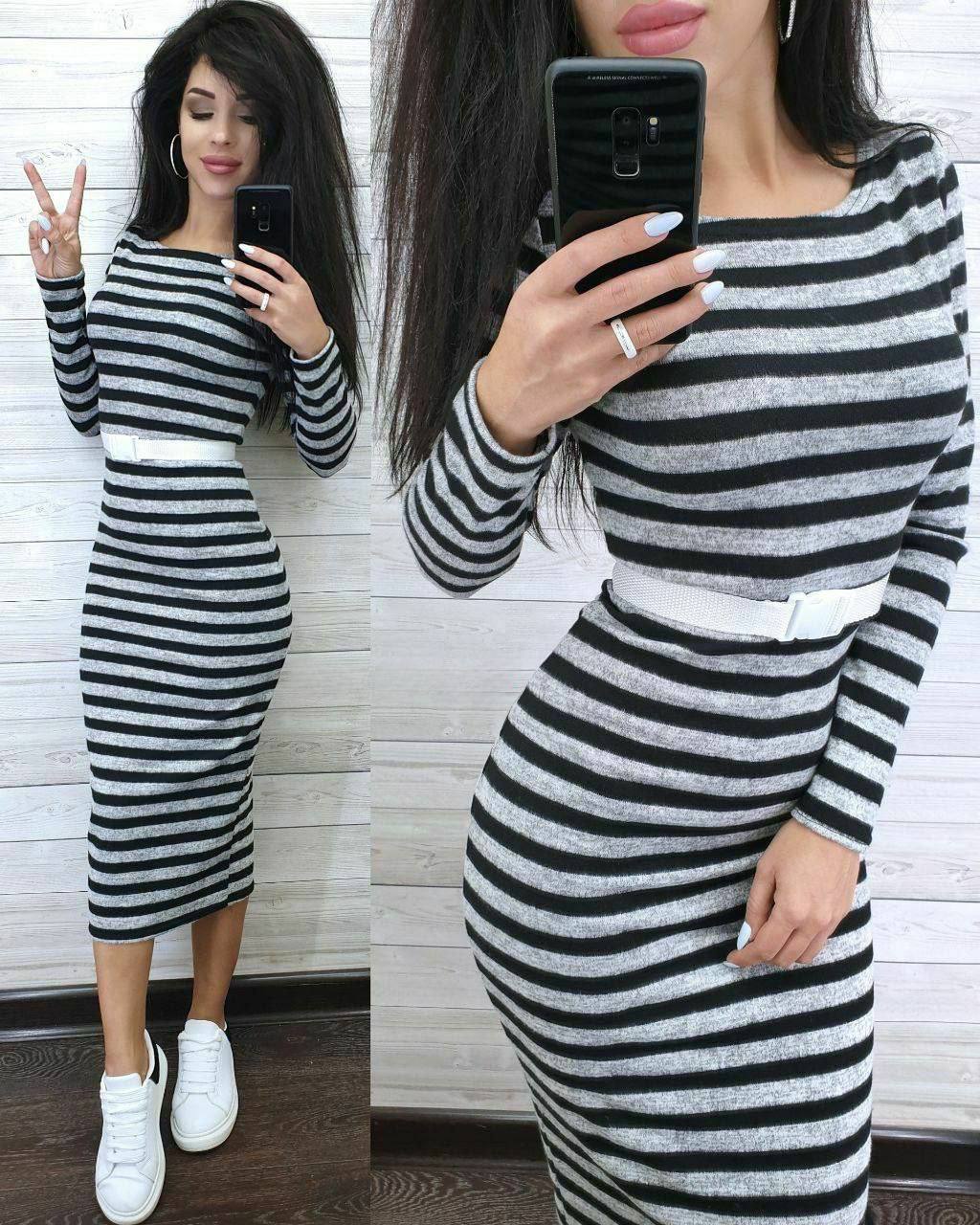 Woman wearing a black and white striped dress taking a mirror selfie.