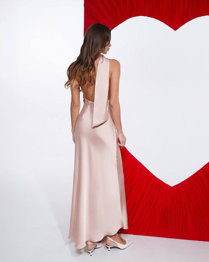 Woman in a pink dress standing in front of a red heart-shaped backdrop