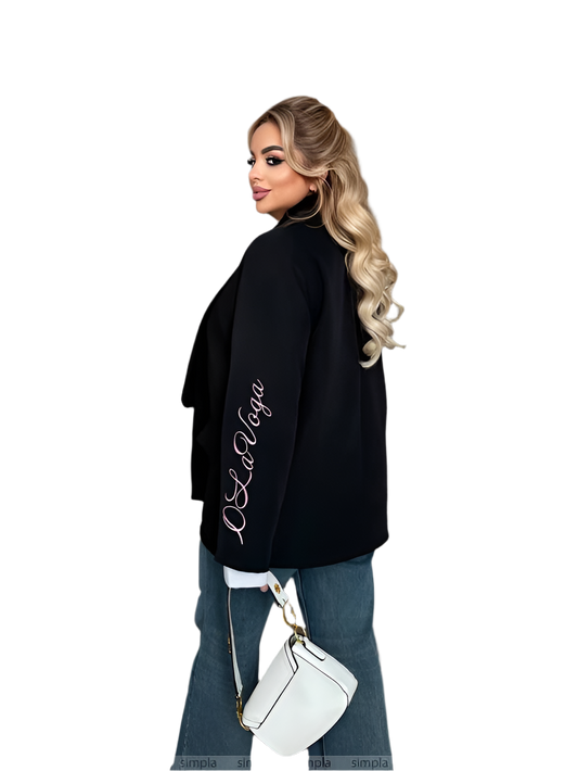 Woman wearing a black oversized sweater with 'La La Vaga' text, holding a white handbag on a white background.