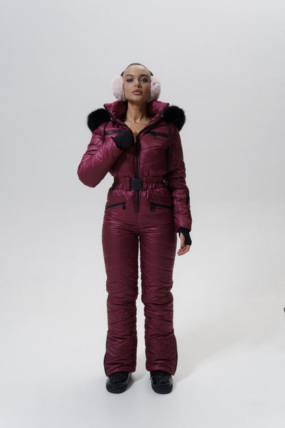 Person wearing a maroon snowsuit with black fur trim on a white background