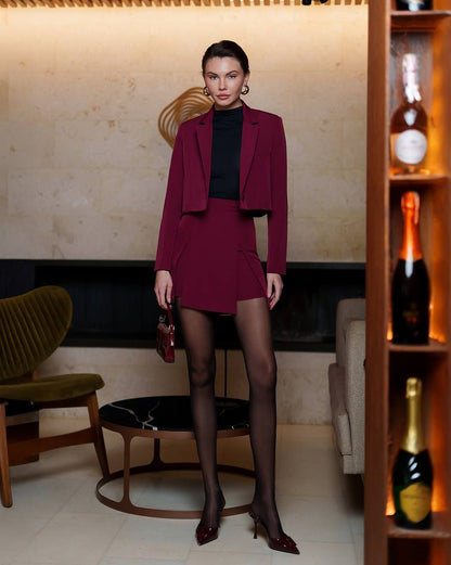 Woman in a burgundy outfit standing in a stylish room with decor elements.