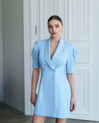 Woman wearing a light blue dress against a white wall