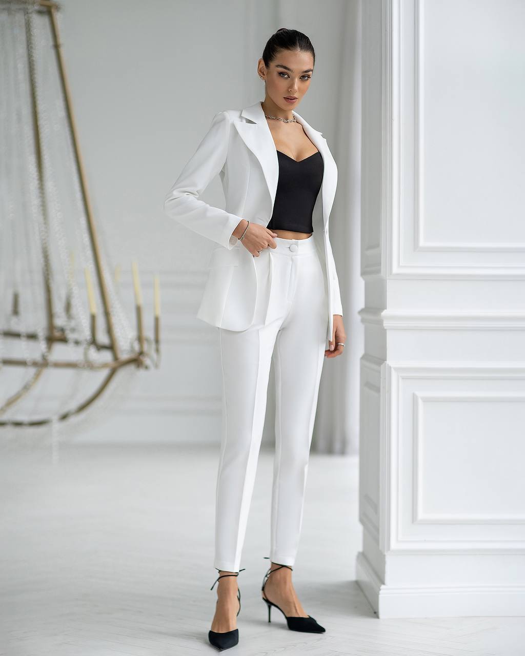 Woman wearing a white suit with black top in a minimalistic setting