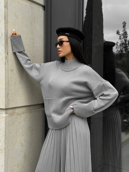 Woman in a gray outfit standing against a building