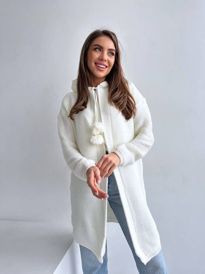 Woman wearing a long white knit cardigan against a plain background
