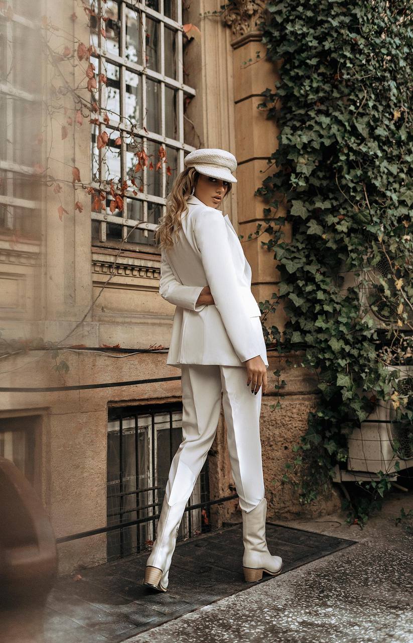 Person in a white suit standing in front of a building with ivy