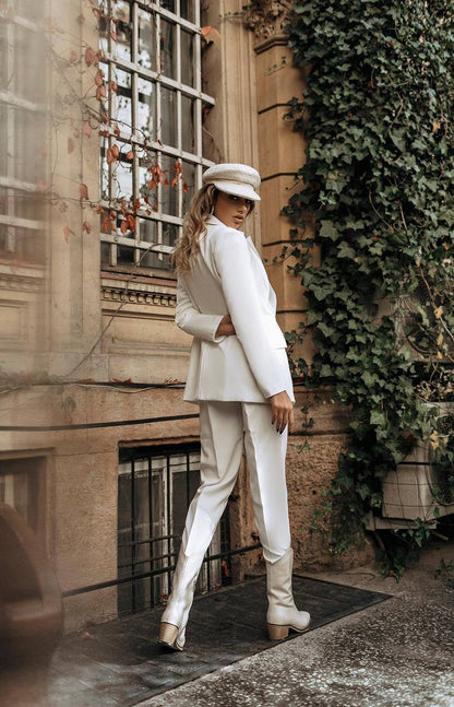 Person in a white suit standing in front of a building with ivy
