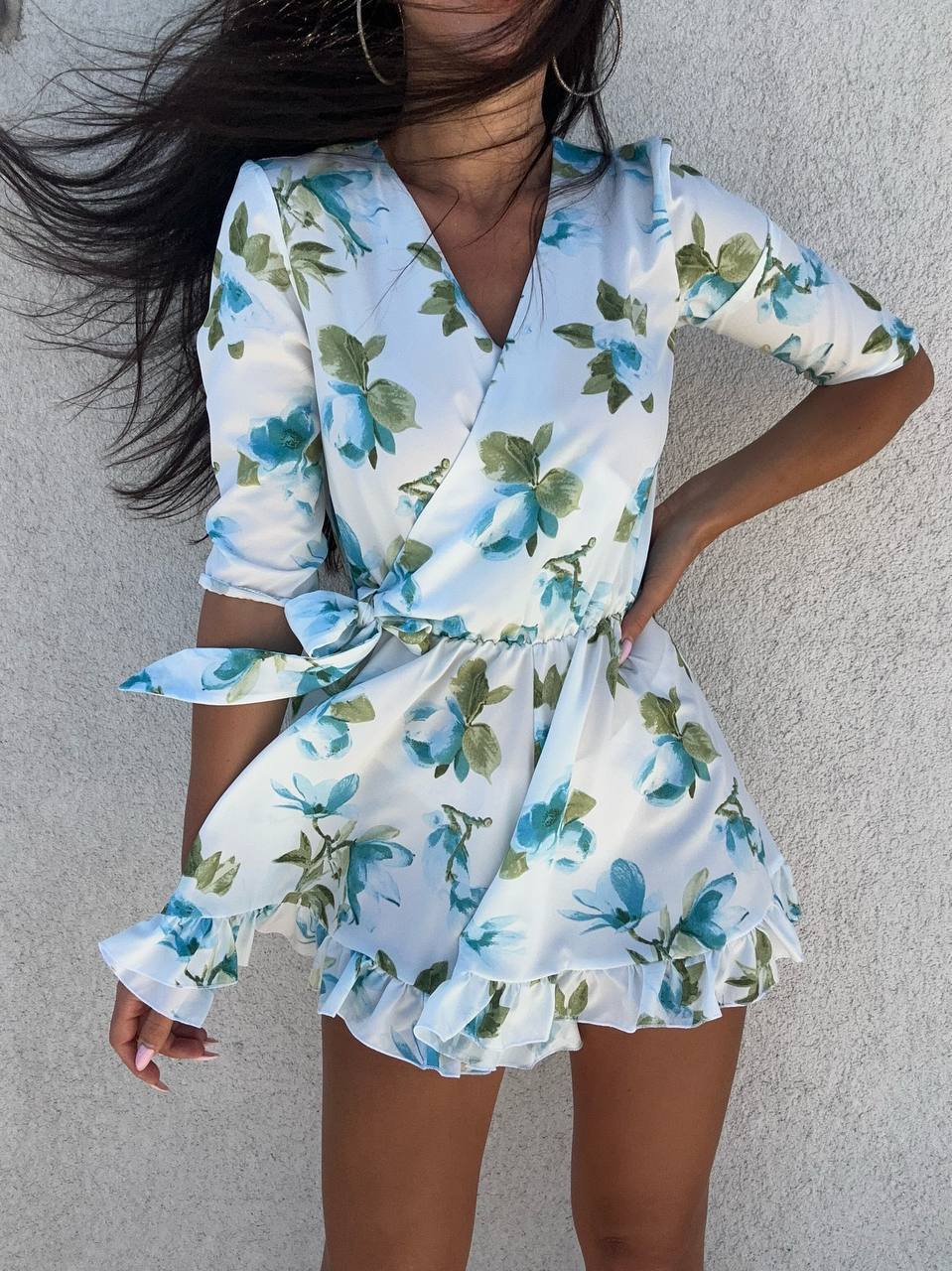 Woman wearing a floral romper against a neutral background
