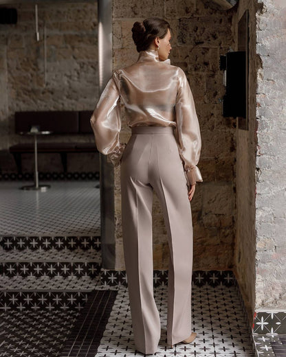 Woman in a beige satin outfit standing in a room with patterned tiles.