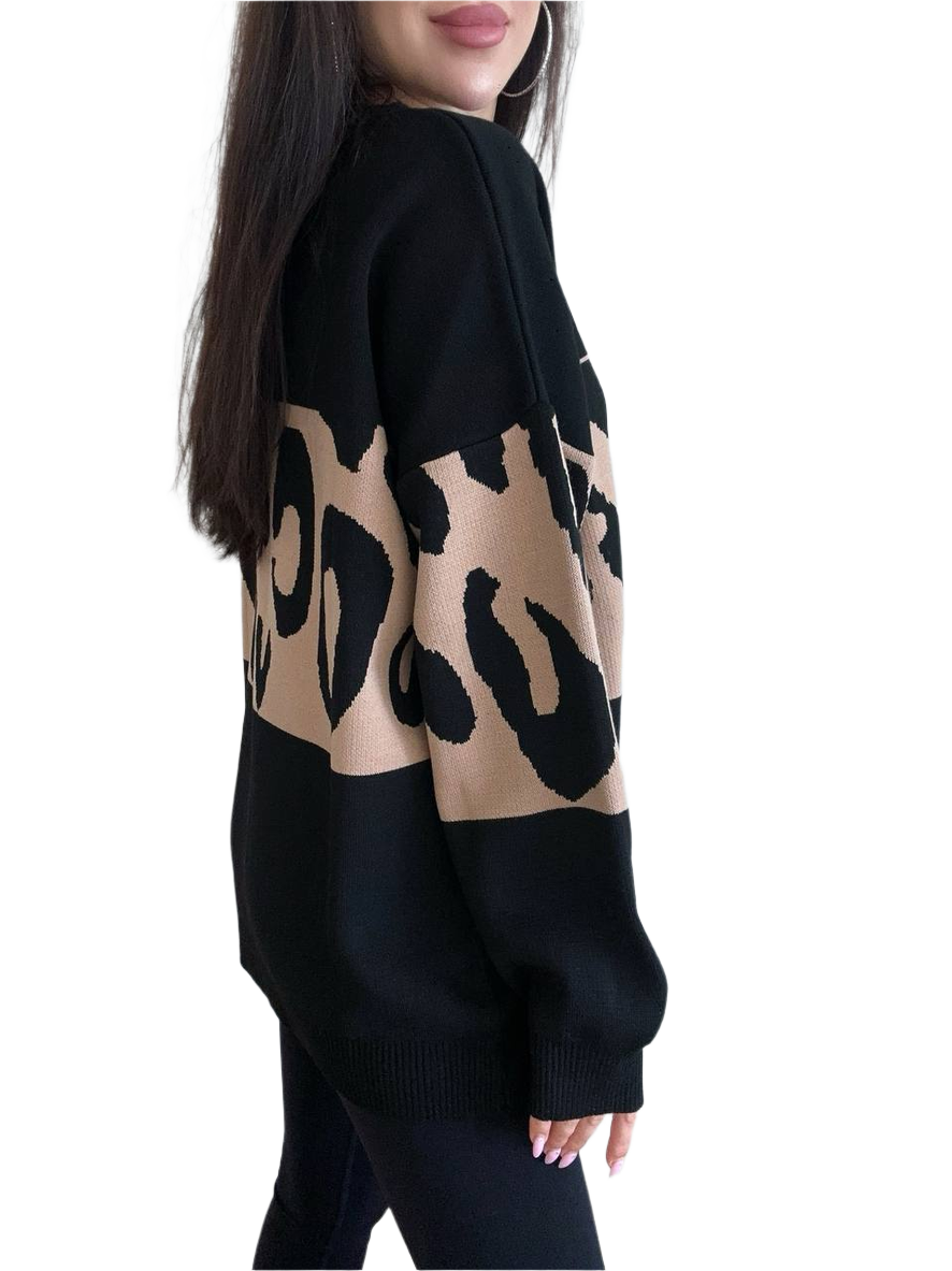 Black sweater with beige leopard print pattern worn by a person on a white background