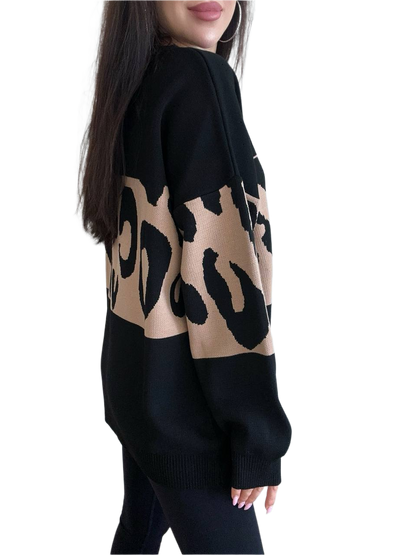 Black sweater with beige leopard print pattern worn by a person on a white background